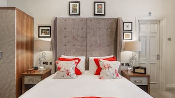 A hotel room with a large bed, two nightstands, a wardrobe, and framed pictures on the wall.
