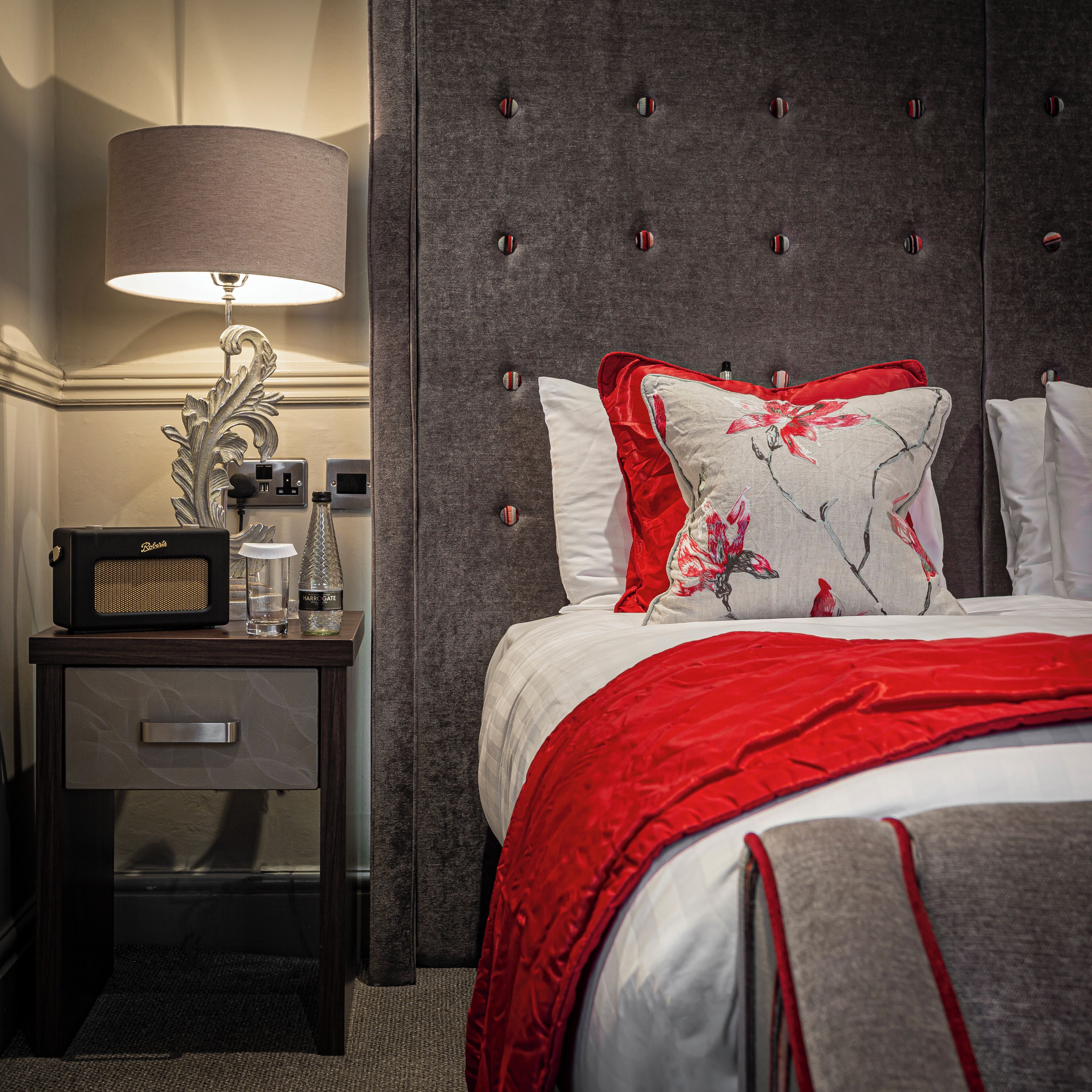 A hotel room with a bed, a nightstand, a lamp, and a radio.