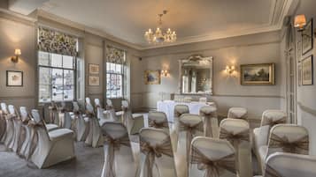 Une salle élégante, avec des rangées de chaises, un lustre et des œuvres d’art encadrées accrochées aux murs.