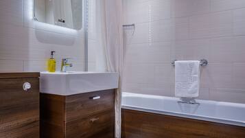 A modern bathroom with a wooden vanity, a white sink, a mirror, a shower, and a toilet.