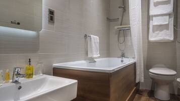 A modern bathroom with two sinks, a bathtub, and a toilet.