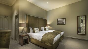 A spacious bedroom with a large bed, a bedside table, a chair, and a framed picture on the wall.