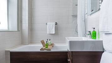 Un baño moderno con bañera, ducha y tocador con espejo.