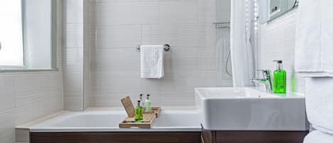 A modern bathroom with a bathtub, a shower, and a vanity with a mirror.