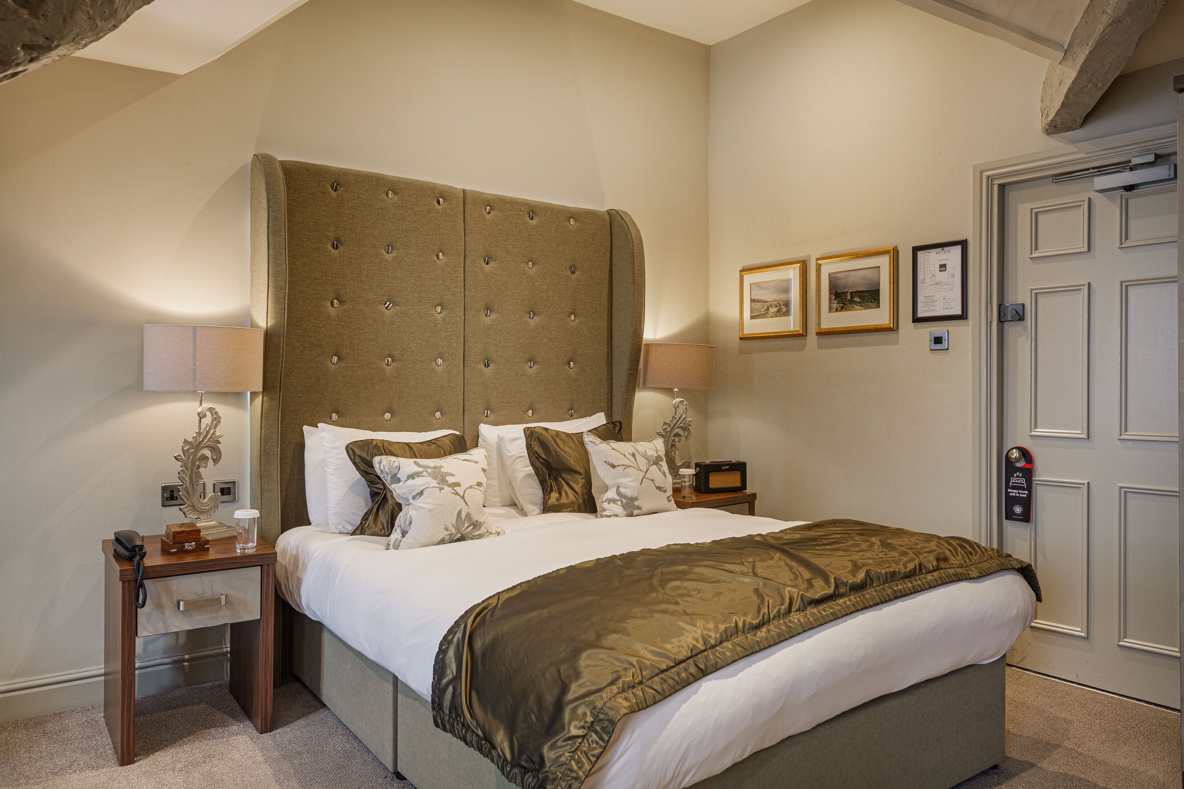 A hotel room with a large bed, bedside tables, lamps, and framed pictures on the wall.