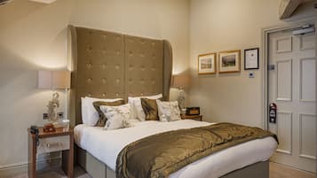 A hotel room with a large bed, bedside tables, lamps, and framed pictures on the wall.