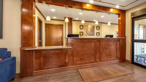A reception area with a wooden reception desk, pendant lighting, and a large mirror. - Comfort Inn Valentine (Valentine)