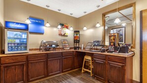A kitchen area with a refrigerator, coffee machine, and a food display.