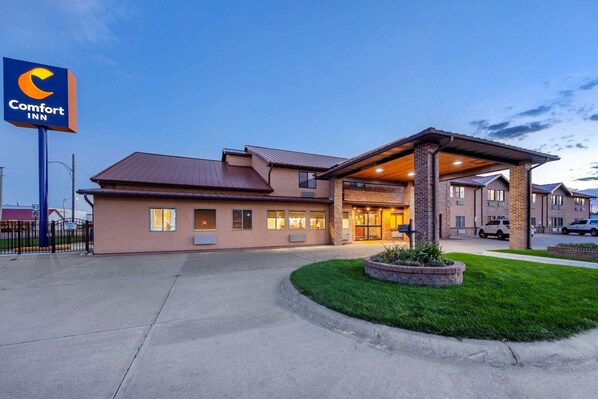 A Comfort Inn hotel with a modern design, featuring a well-lit entrance and a landscaped area with a small garden.