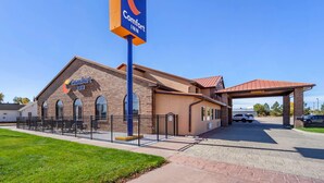 A Comfort Inn hotel with a brick facade, a covered entrance, and a fenced outdoor area.