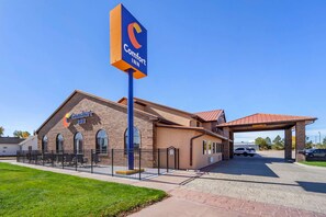 A Comfort Inn hotel with a brick facade, a covered entrance, and a fenced outdoor area.
