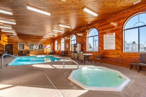 A wooden interior with a pool, hot tub, and seating area.