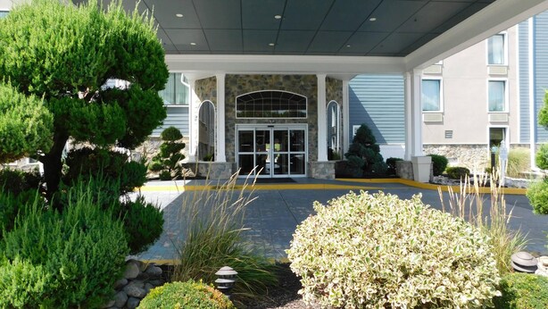 A hotel entrance with a covered walkway, stone facade, and a large glass door. - Comfort Inn & Suites Glen Mills - West Chester (Glen Mills)