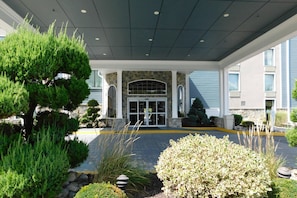 A hotel entrance with a covered walkway, stone facade, and a large glass door. - Comfort Inn & Suites Glen Mills - West Chester (Glen Mills)