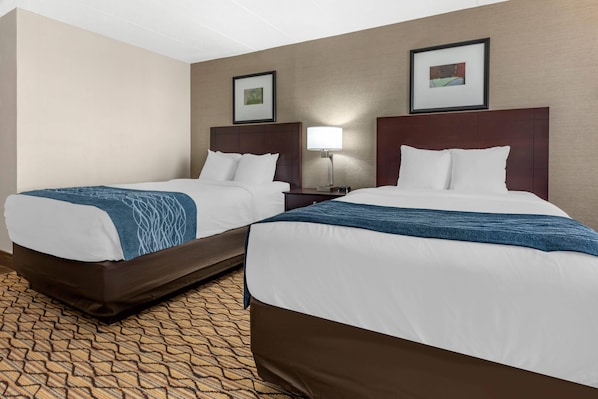 Two double beds with headboards, a nightstand with a lamp, and a patterned carpet. - Comfort Inn & Suites Glen Mills - West Chester (Glen Mills)