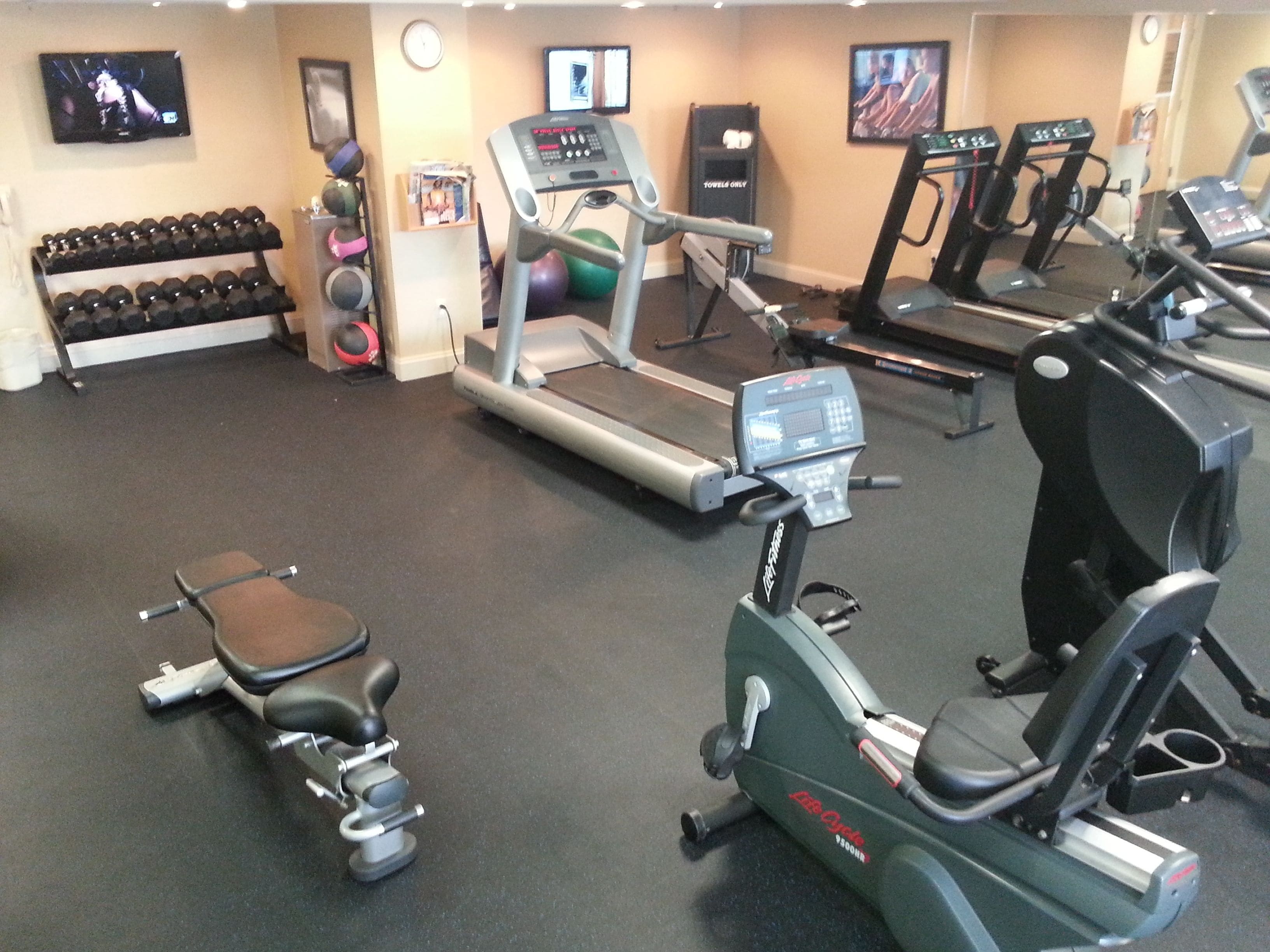A gym with treadmills, an elliptical, and free weights.