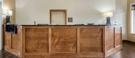 Una recepción con encimera de madera, un televisor de pantalla plana y un espejo enmarcado en la parte superior.