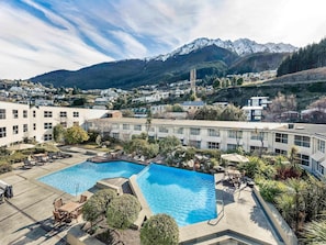 Ett hotell med två pooler, en uteplats och utsikt över snöklädda berg.