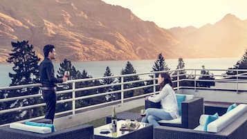 Ein Paar auf einem Balkon mit Blick auf einen See und Berge im Hintergrund.
