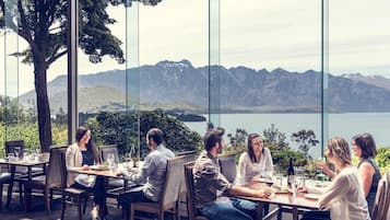 A group of people dining at a table with a scenic mountain and lake view.
