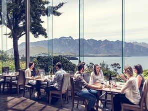 A group of people dining at a table with a scenic mountain and lake view. - Mövenpick Queenstown (Queenstown)