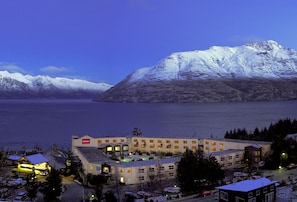 A hotel with multiple floors, a swimming pool, and a view of snow-capped mountains. - Mercure Queenstown Resort (Queenstown)