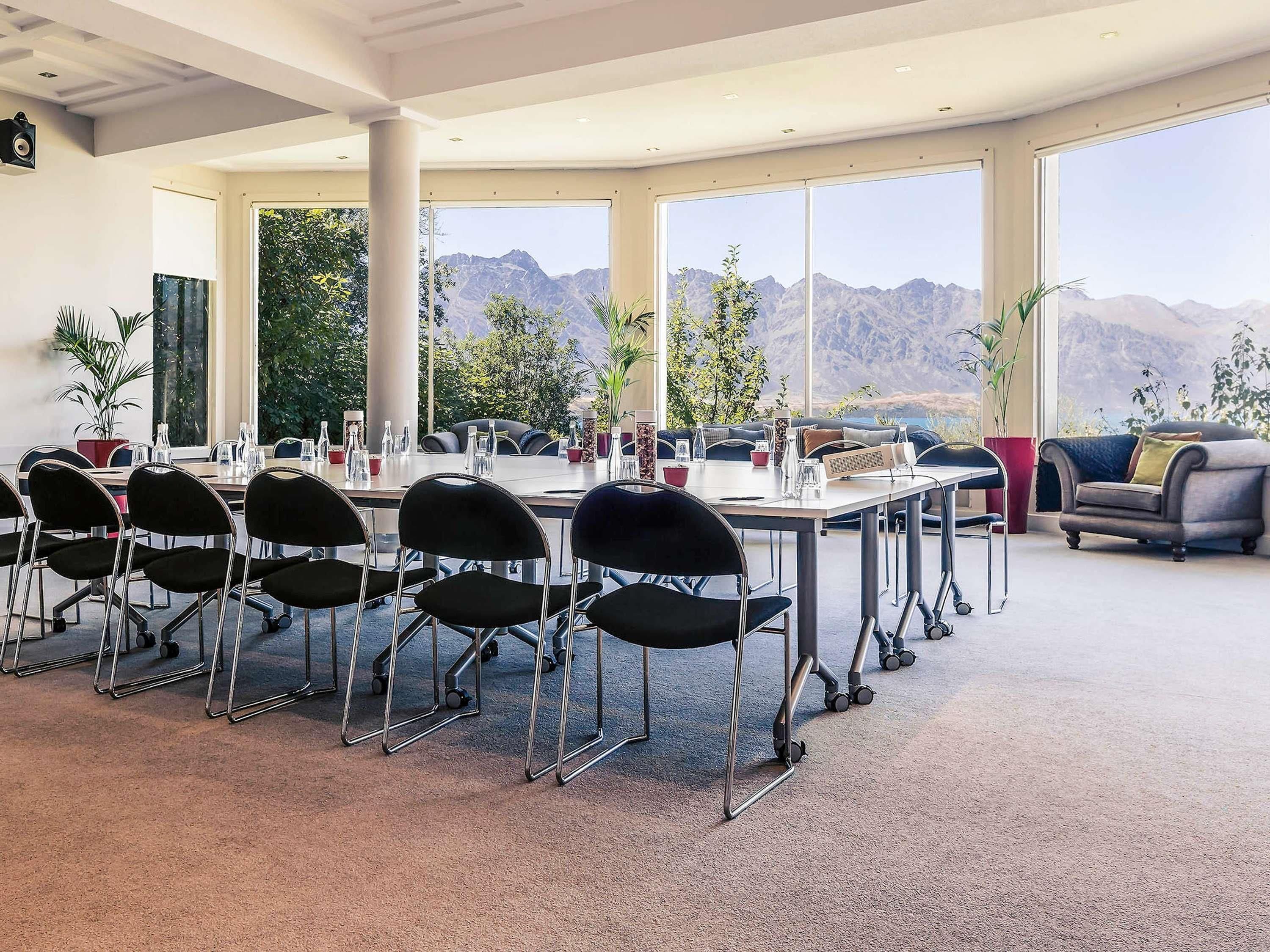 A conference room with a table, chairs, and a view of mountains.