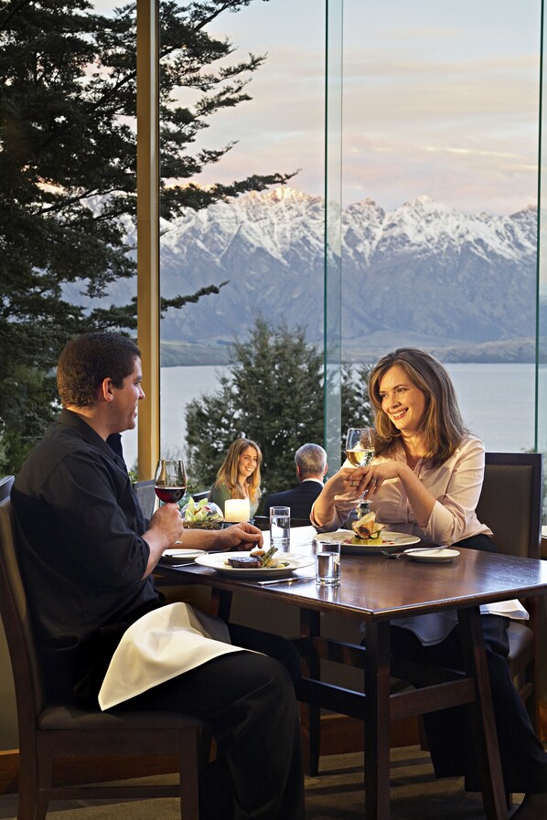 A dining table with a view of snow-capped mountains and a lake. - Mercure Queenstown Resort (Queenstown)