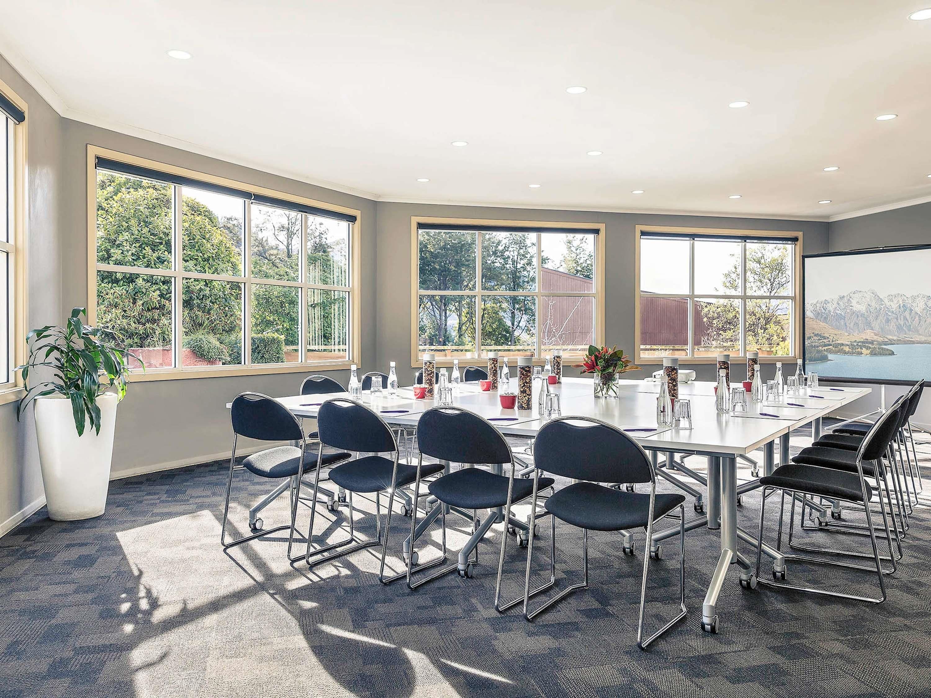 Une salle de conférence dotée d’une grande table, de chaises et de fenêtres offrant une vue panoramique.