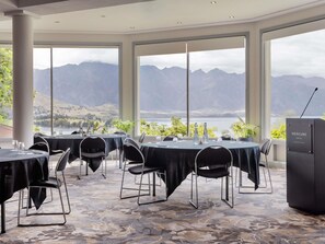 A conference room with tables set for a meeting, large windows with a mountain view, and a podium labeled 'Mercure Hotel.' - Mövenpick Queenstown (Queenstown)