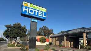 Letrero del Hotel Palm Inn con logotipo de palmera, ubicado en Magnolia Ave, 10518.