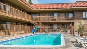 Un hotel con piscina, varios balcones y cielo despejado.