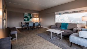 Una sala de estar moderna con un sofá, sillones, una mesa de centro y una zona de comedor con sillas y una mesa.