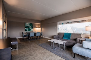 Una sala de estar moderna con un sofá, sillones, una mesa de centro y una zona de comedor con sillas y una mesa.