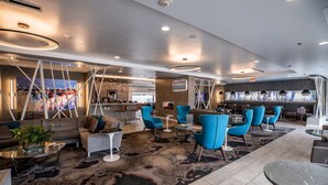 Un moderno vestíbulo de hotel con una zona de estar que incluye sofás y sillones, un área de bar y un amplio ventanal con vistas.