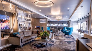 A modern hotel lobby with a sofa, chairs, a coffee table, and a TV.