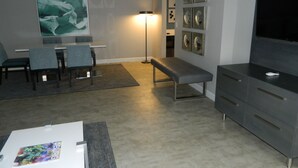 Una sala de estar moderna con comedor, un banco, un televisor de pantalla plana y obras de arte en las paredes.