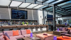 A modern bar area with a cityscape view, multiple seating options, and a variety of bar stools.