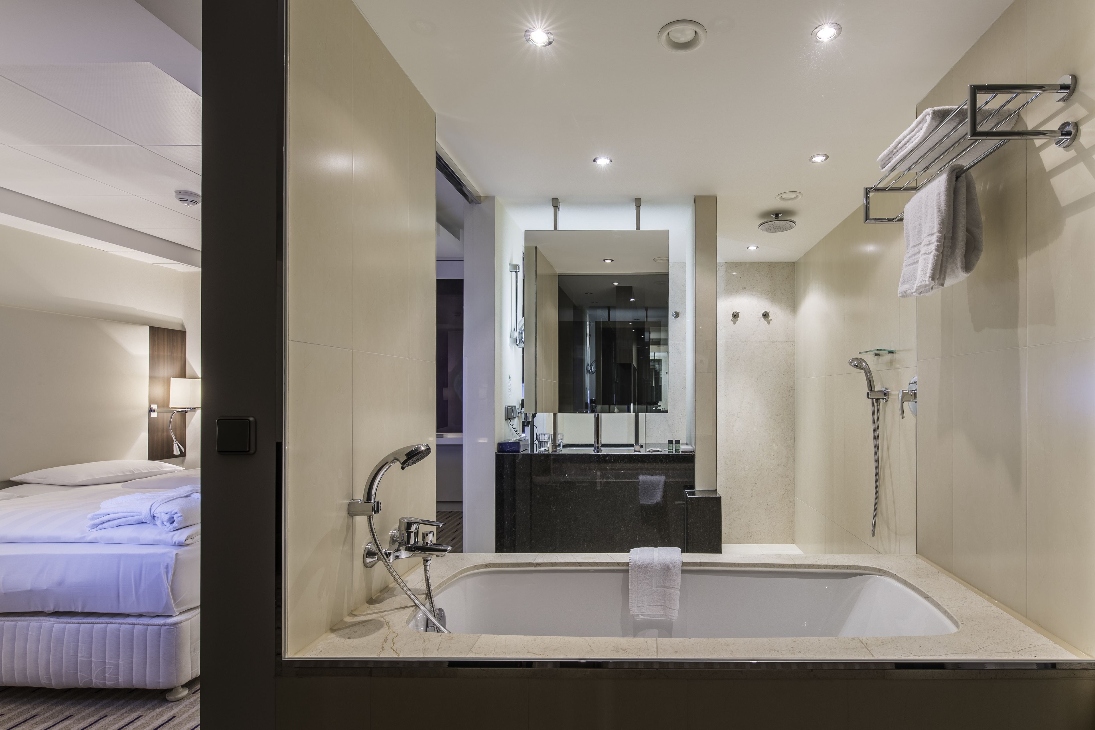 A modern hotel bathroom with a large bathtub, a shower, and a vanity with a mirror.
