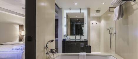 A modern hotel bathroom with a large bathtub, a shower, and a vanity with a mirror.