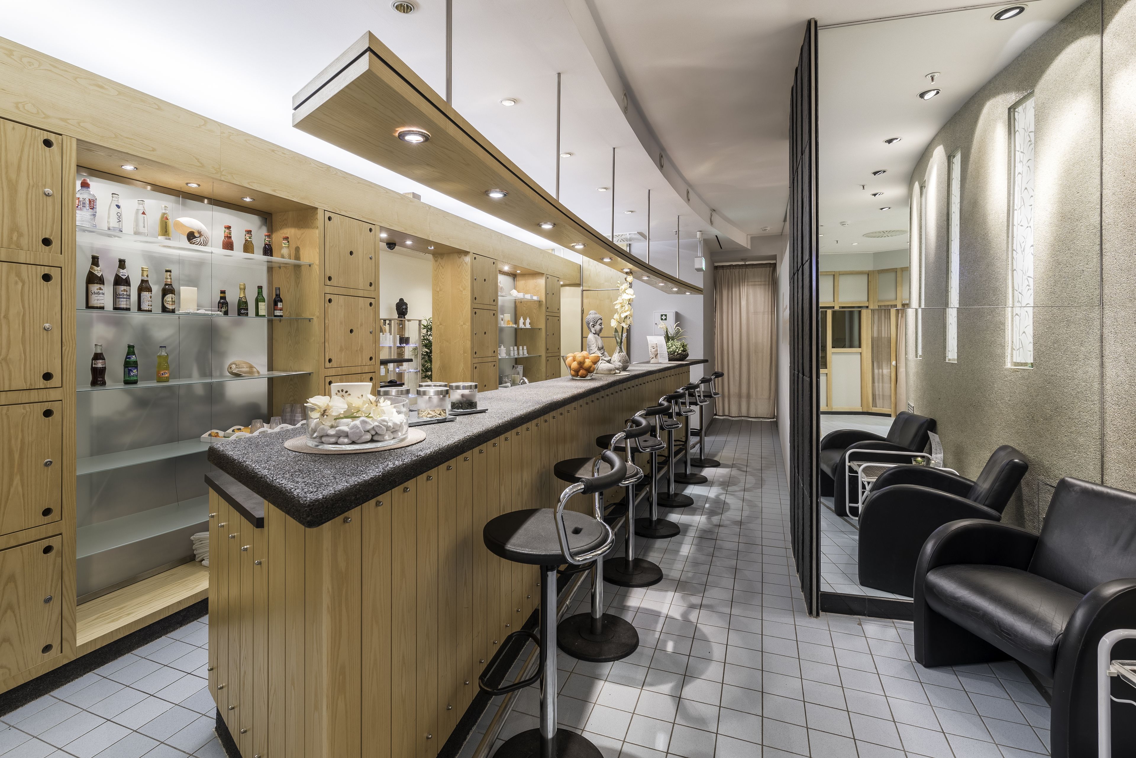 A bar area with stools and a counter displaying various bottles.