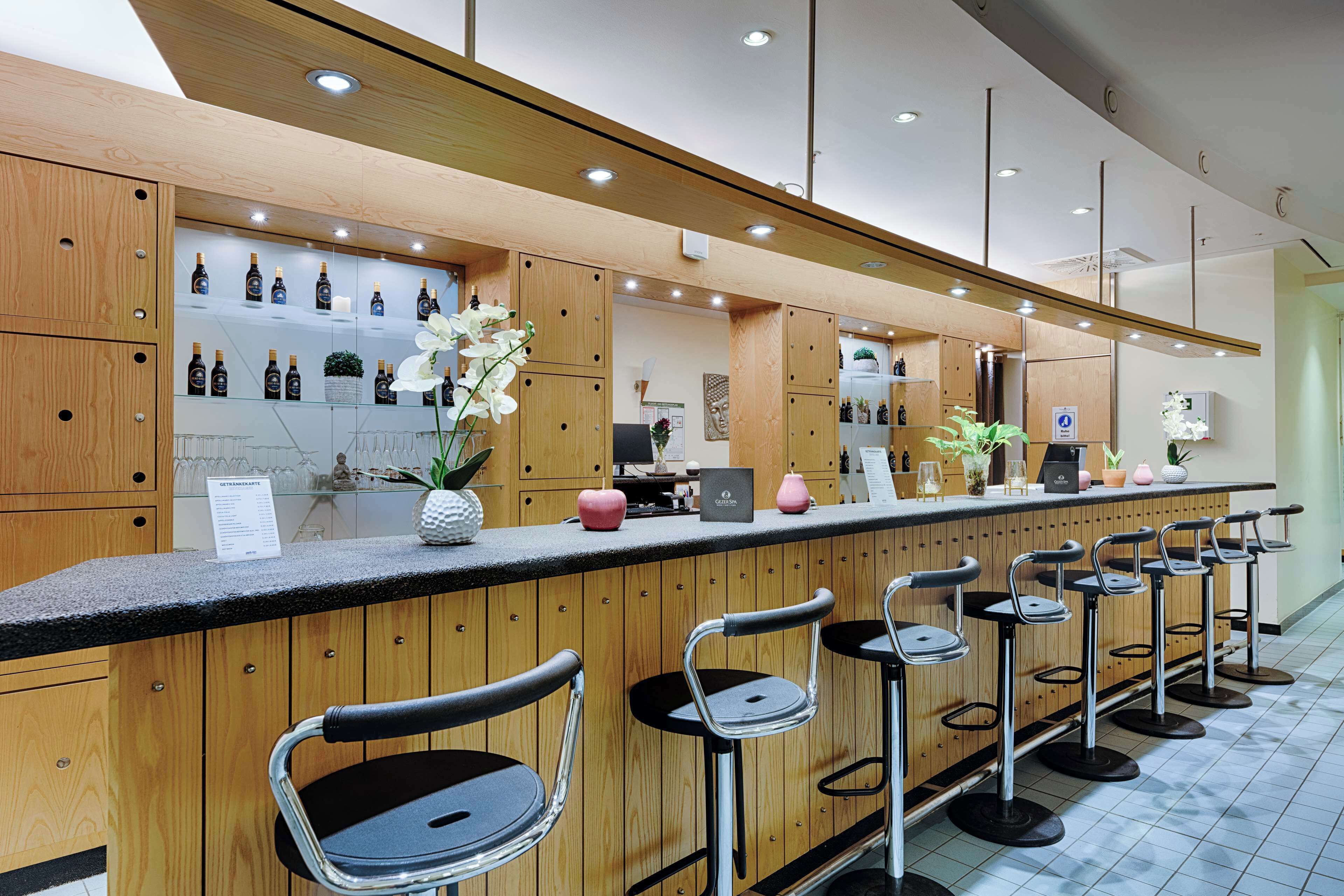 Una zona de bar moderna con armarios de madera, una barra con un menú y taburetes.