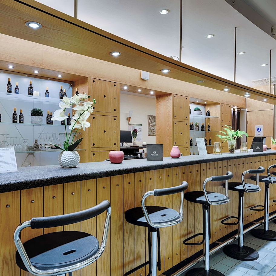 A modern bar area with wooden cabinetry, a counter with a menu, and bar stools.