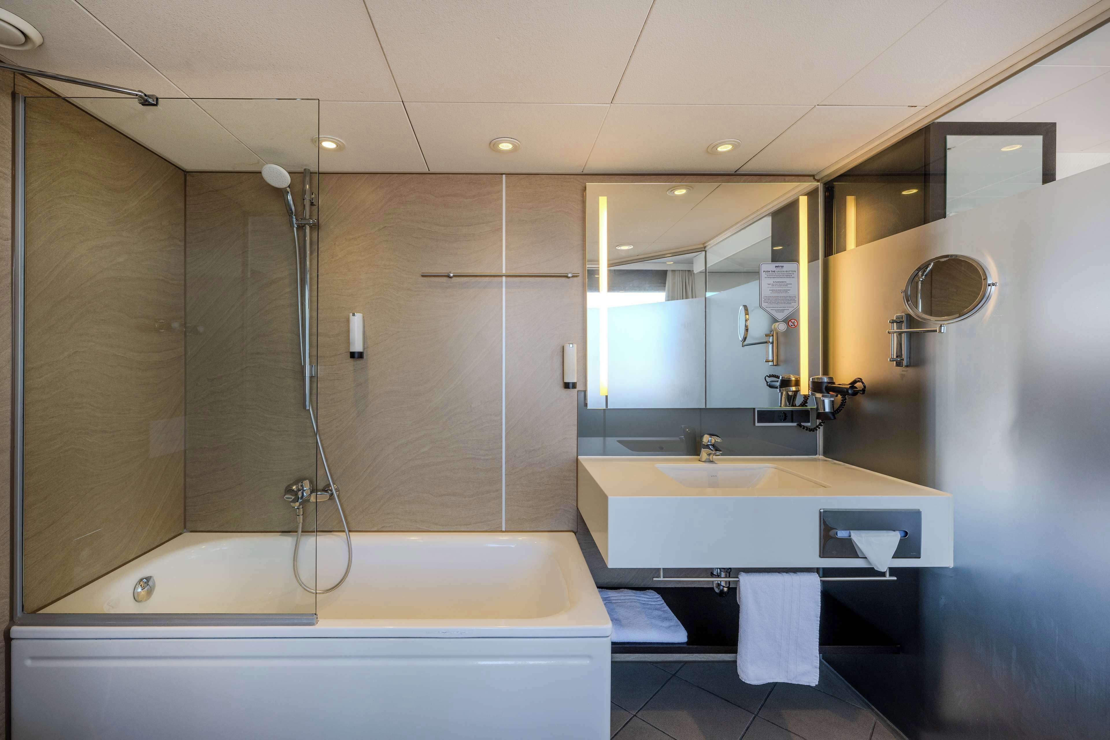 A modern bathroom with a bathtub, a shower, and a vanity with a mirror.