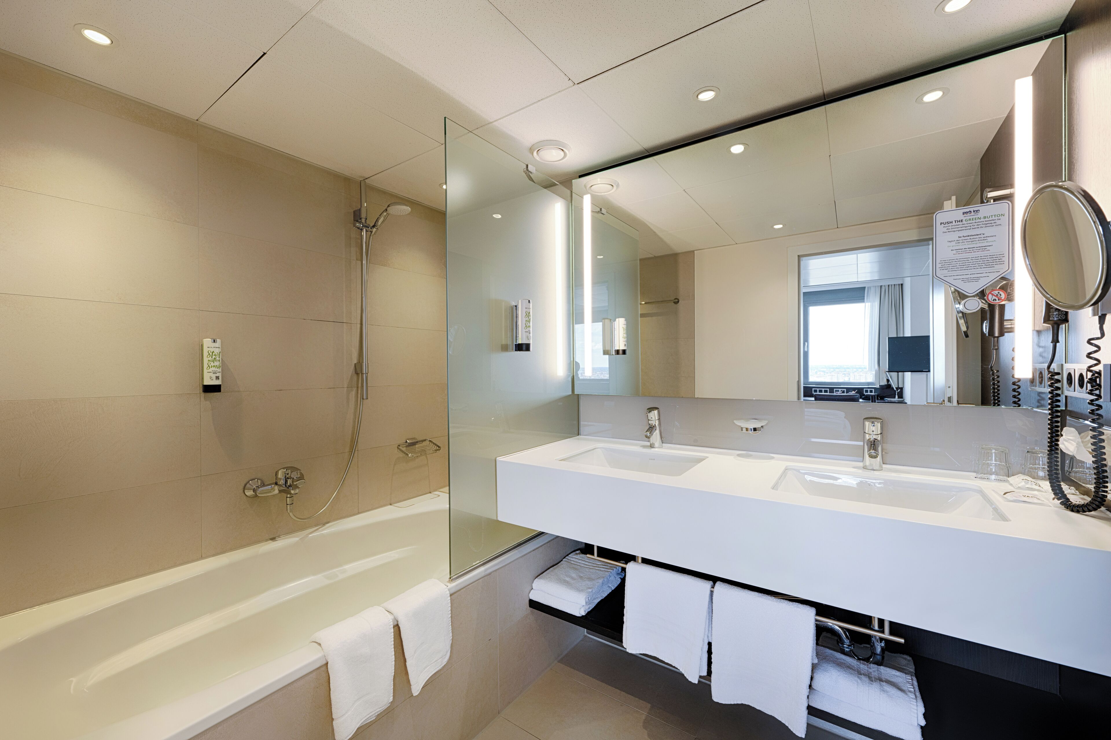 Un baño moderno con ducha de vidrio, una bañera blanca y un amplio tocador con espejo.