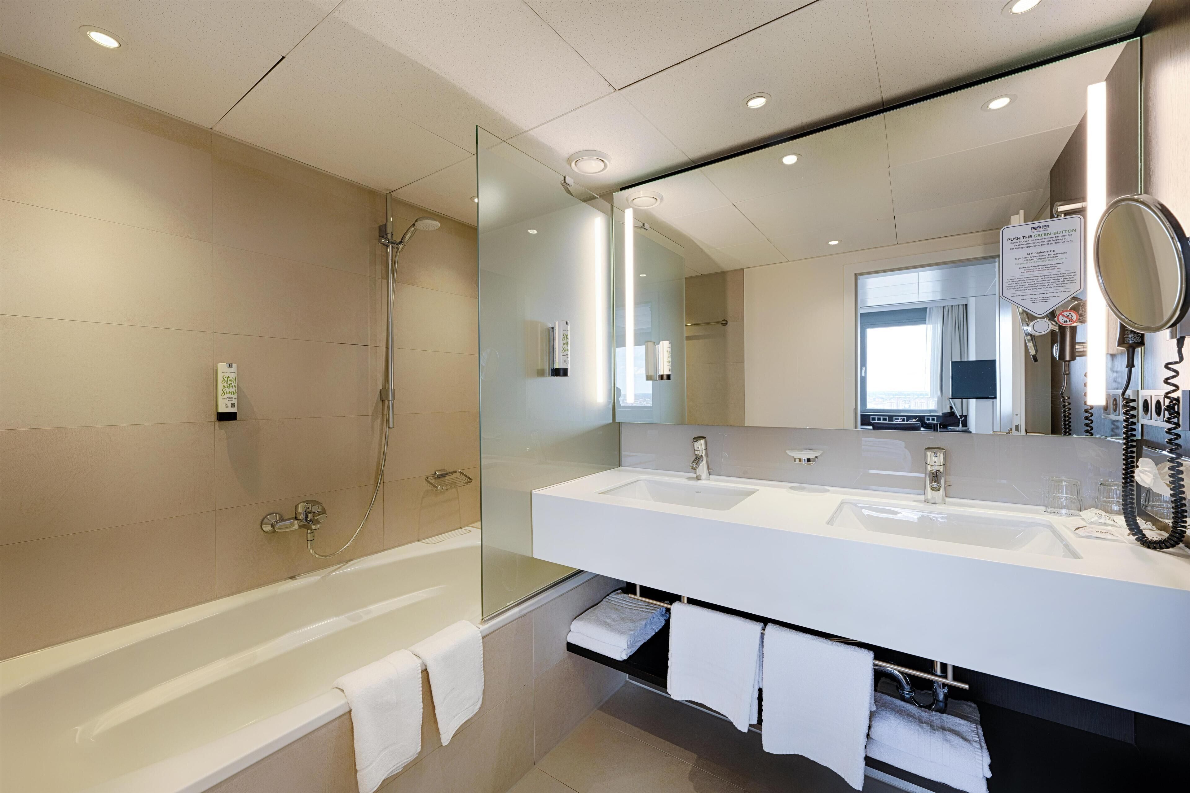 Un baño moderno con ducha de vidrio, un lavamanos grande de color blanco y un espejo, y una bañera.