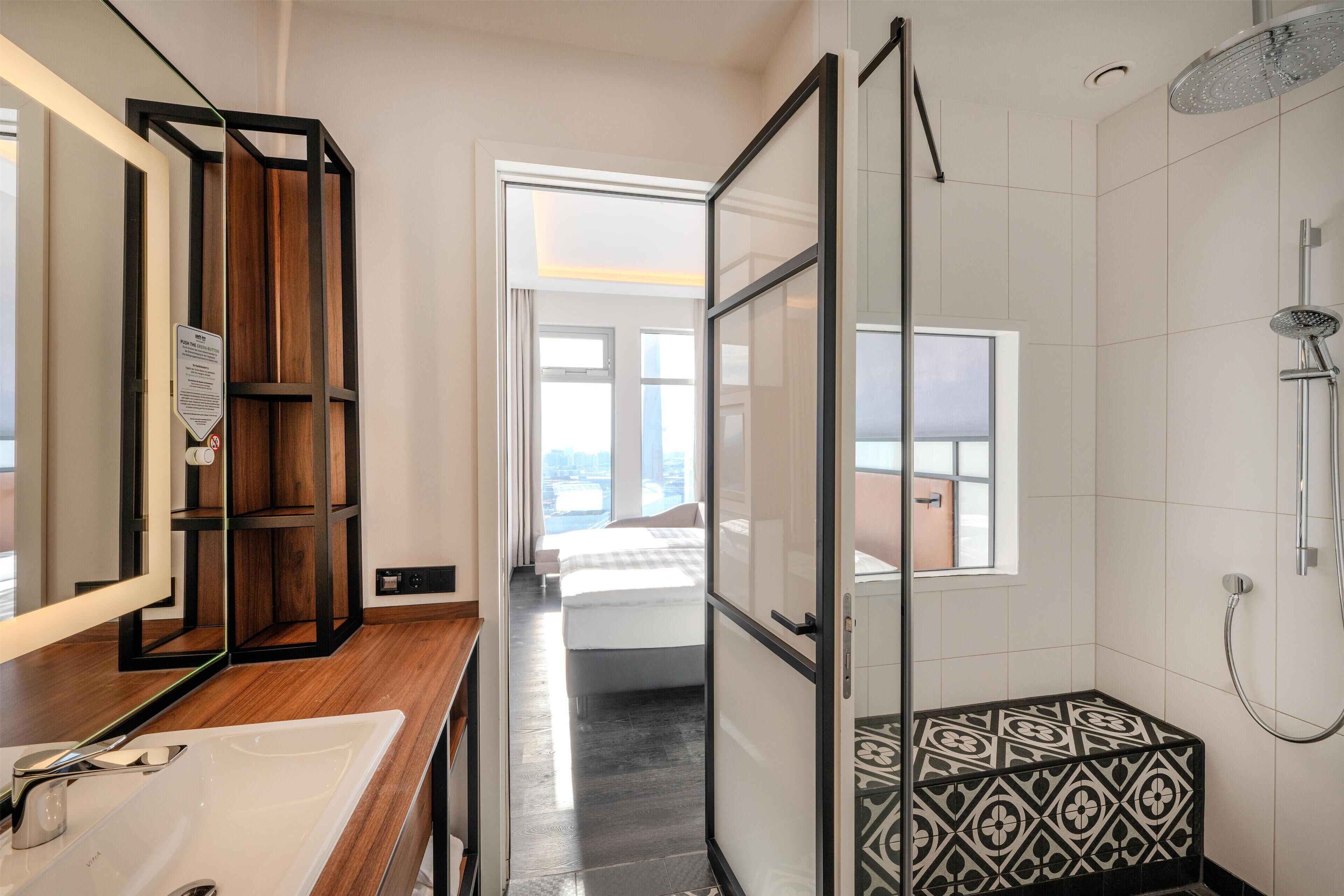 Un baño moderno con cabina de ducha de vidrio, tocador de madera y un espejo grande.