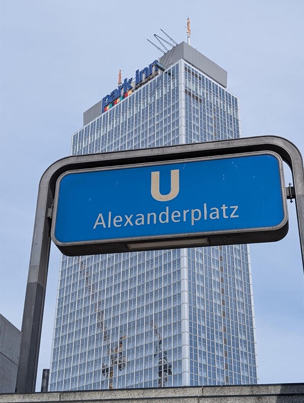A blue sign with "Alexanderplatz" and a building with "Park Inn" sign.