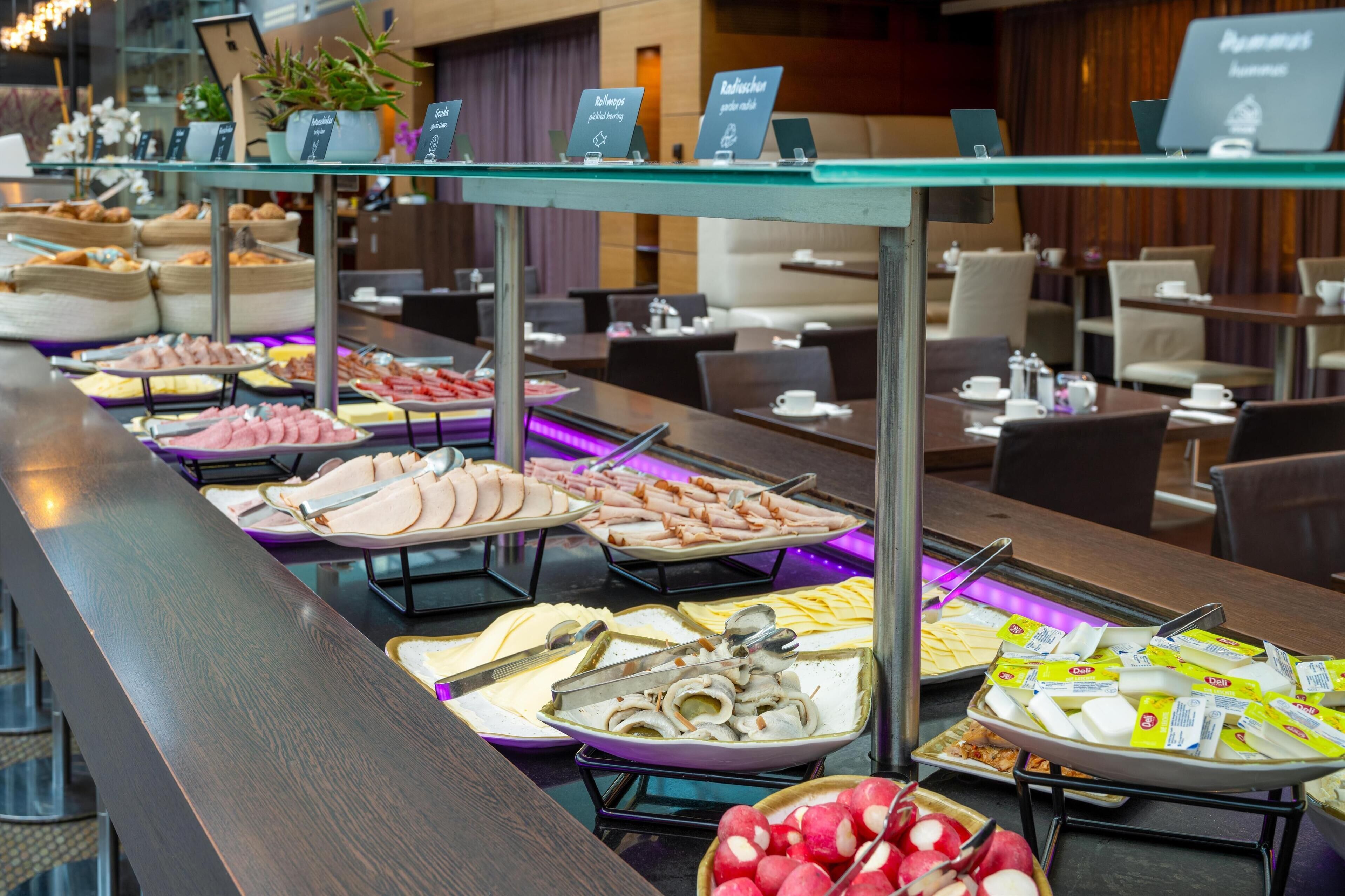 A buffet with various food options including meats, cheeses, and fruits.