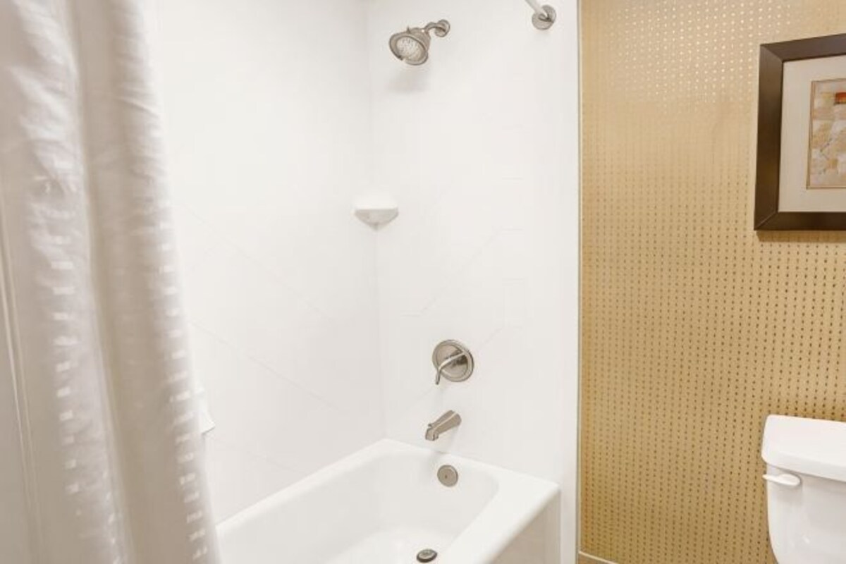 Een badkamer met een bad, toilet en douchegordijn.